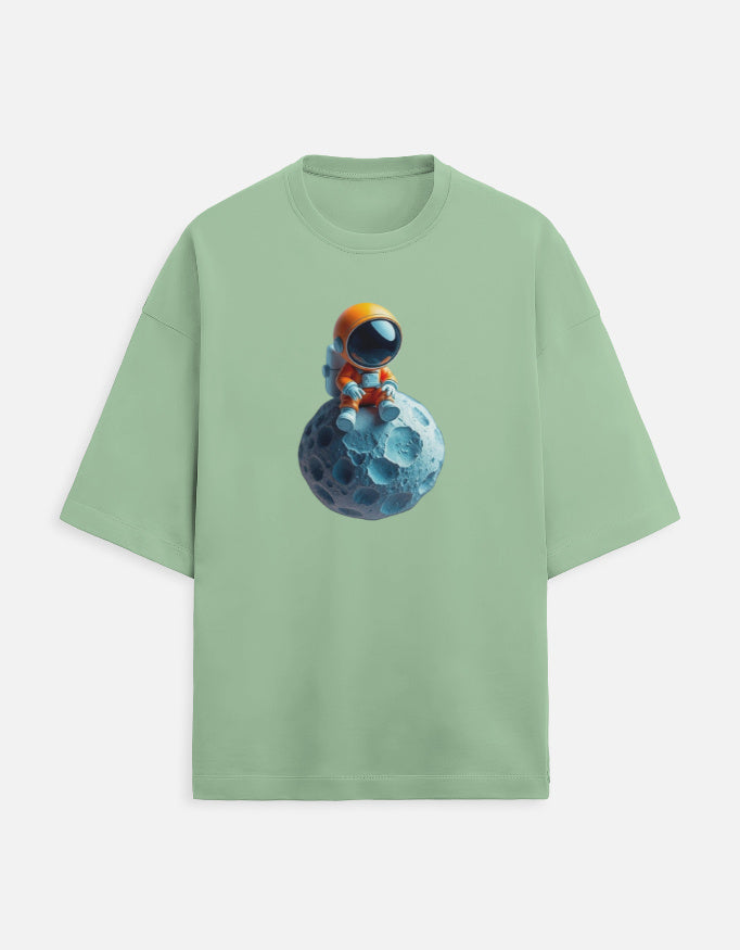 Green t-shirt with cute astronaut in orange suit sitting on a blue moon graphic