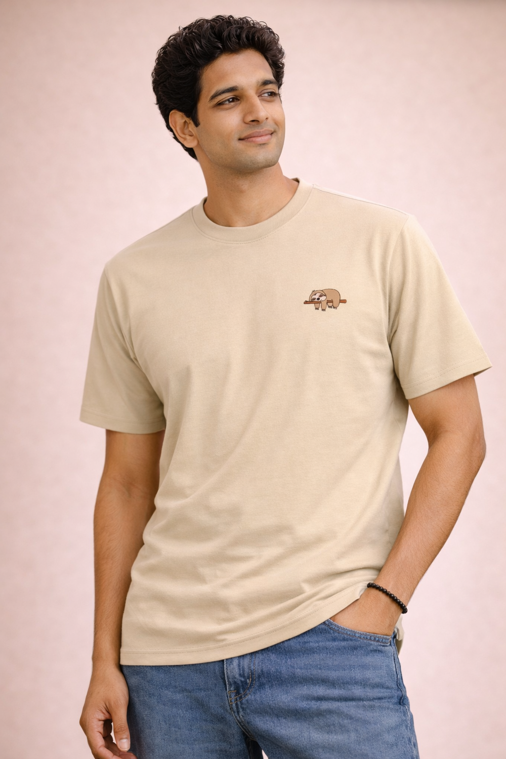 Man wearing a beige t-shirt with a logo on a pink background
