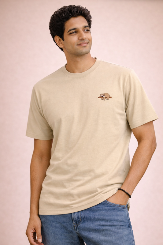 Man wearing a beige t-shirt with a logo on a pink background