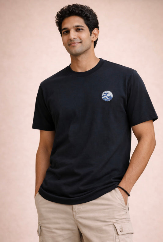 Man wearing a black t-shirt with a small logo on a beige background