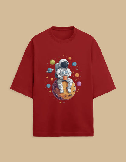 Red t-shirt with astronaut sitting on planet, holding cup, surrounded by colorful planets