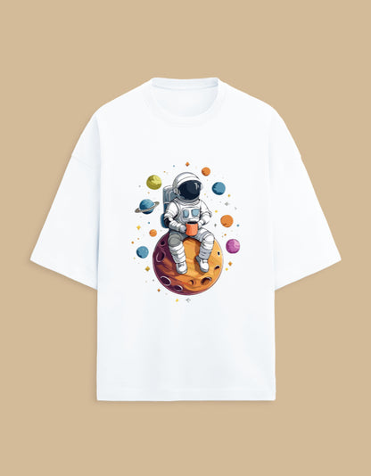 White T-shirt with astronaut holding coffee, sitting on planet, surrounded by colorful planets