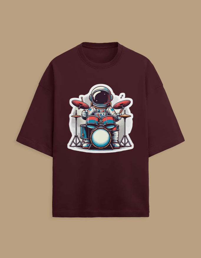 Burgundy t-shirt with cartoon astronaut playing drums graphic on front, beige background
