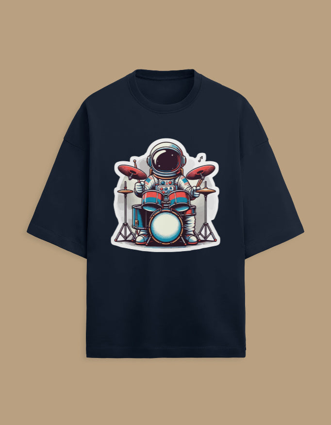 Black t-shirt with cartoon astronaut playing drums graphic, flat lay on tan background
