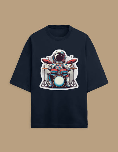 Black t-shirt with cartoon astronaut playing drums graphic, flat lay on tan background