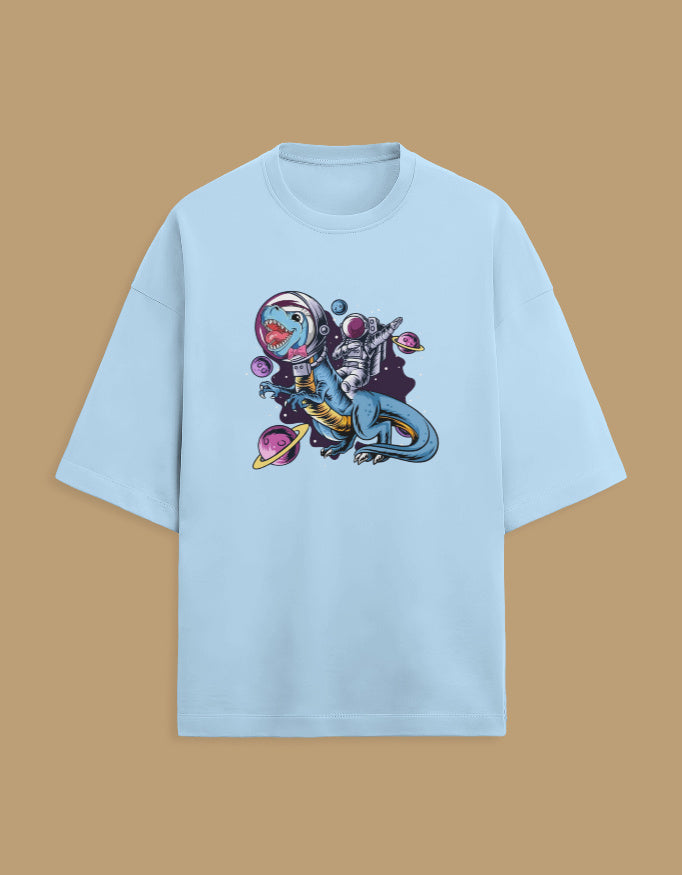Light blue t-shirt with astronaut dinosaur and space planets graphic, displayed on brown background