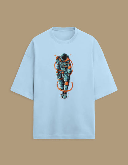 Light blue t-shirt with graphic astronaut design on front, isolated on tan background