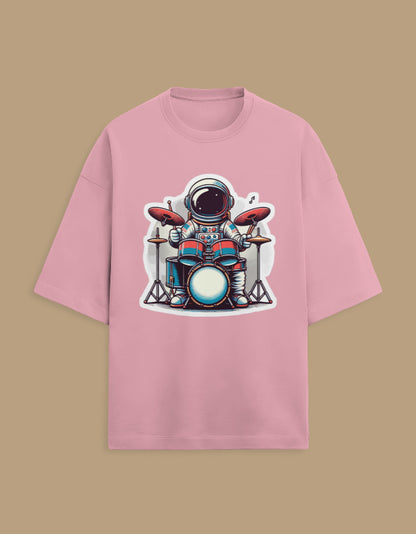 Pink t-shirt with cartoon astronaut playing drums graphic, laid on beige background