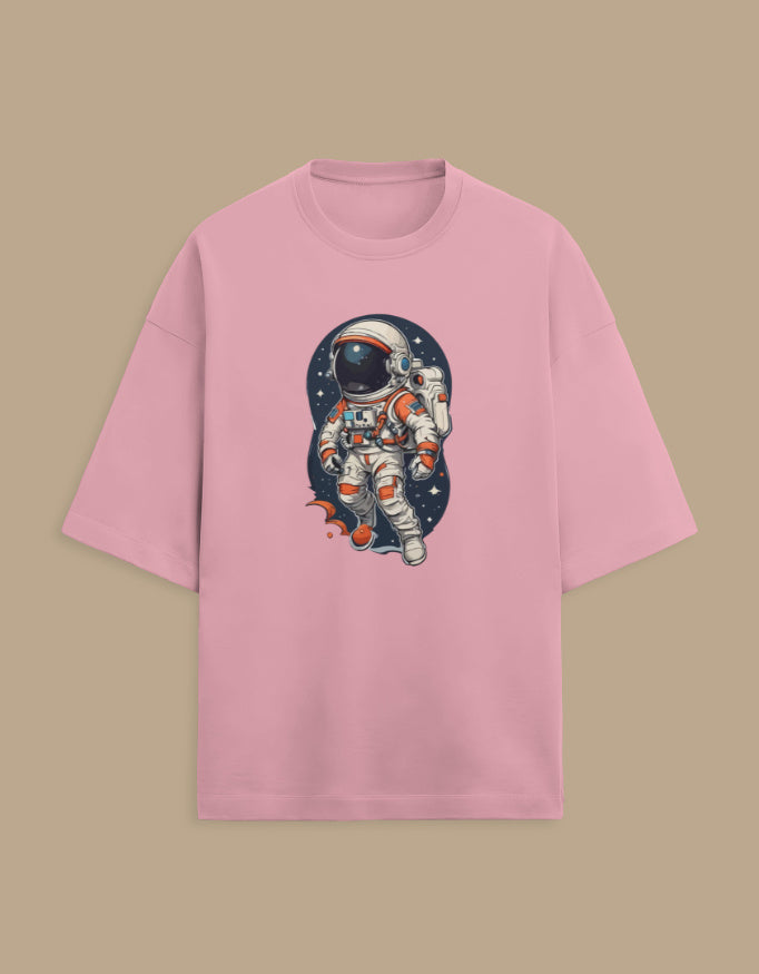 Pink t-shirt with cartoon astronaut space graphic, front view on beige background