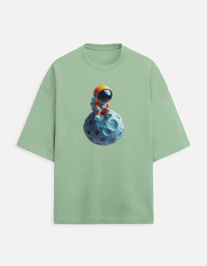 Green t-shirt with cute astronaut in orange suit sitting on a blue moon graphic