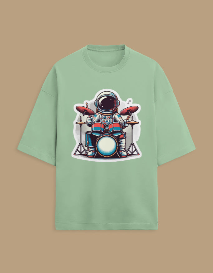 Mint green t-shirt with cartoon astronaut playing drums graphic, beige background