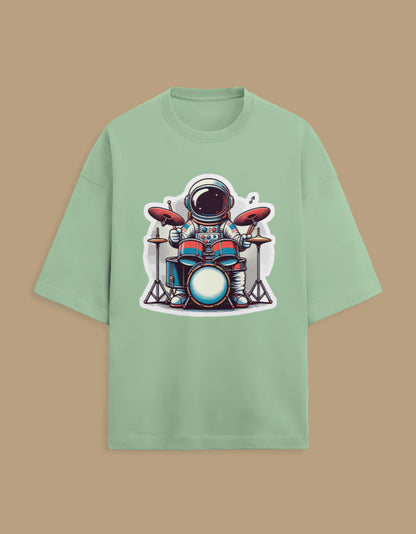 Mint green t-shirt with cartoon astronaut playing drums graphic, beige background