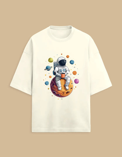 White t-shirt with astronaut drinking coffee on a planet, surrounded by colorful planets