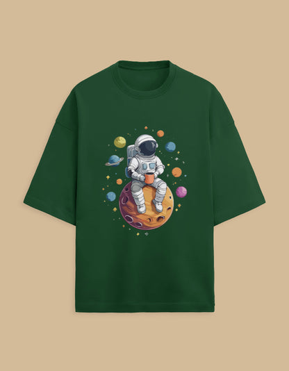 Green t-shirt with astronaut sitting on planet cartoon, surrounded by colorful space elements
