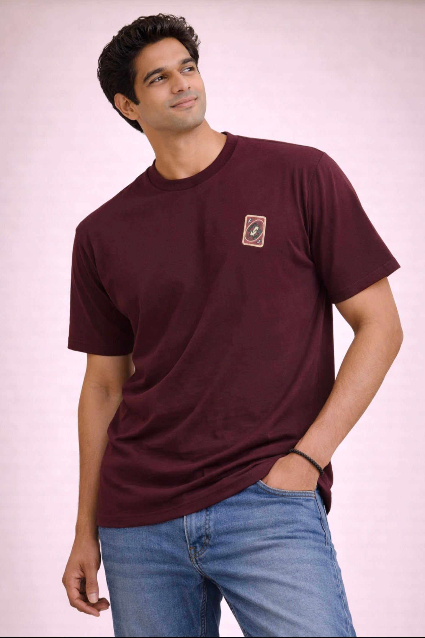 Man wearing a maroon t-shirt with a small logo on a plain background