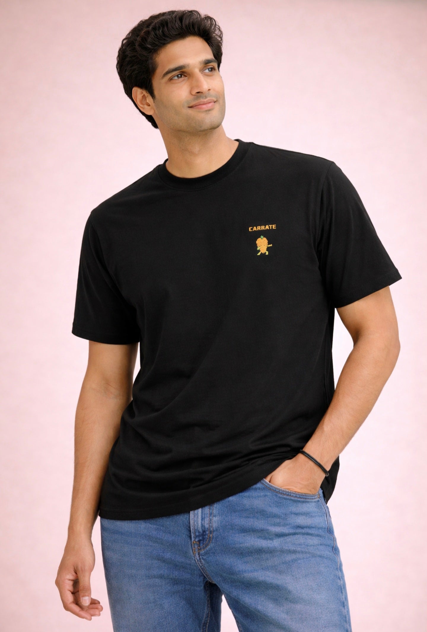 Man wearing a black t-shirt with a small logo on a pink background