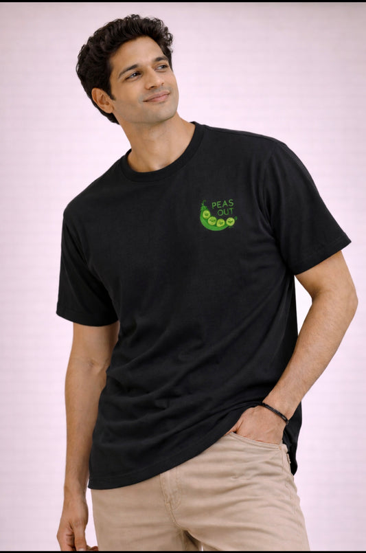 Man wearing a black t-shirt with a green graphic on a light pink background