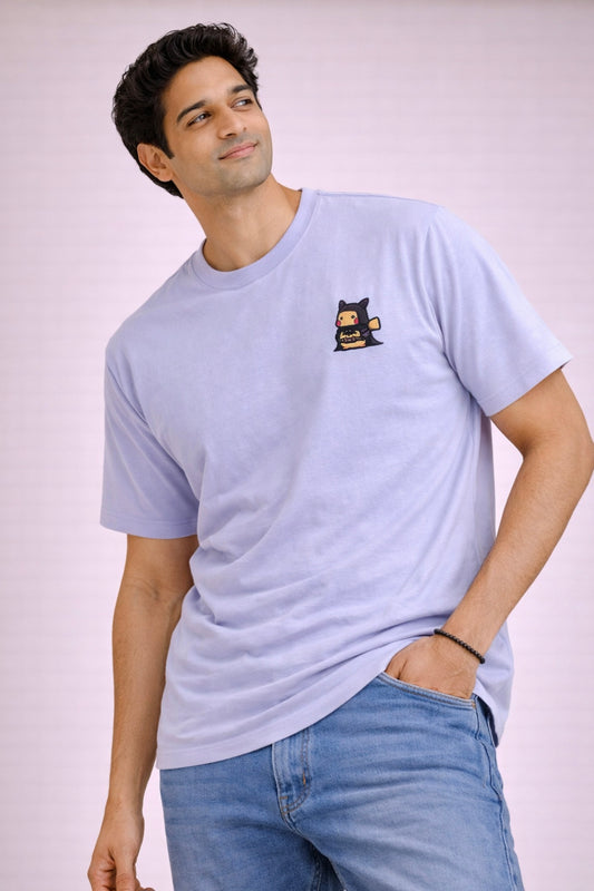 Man wearing a light blue t-shirt with a small graphic on a plain background