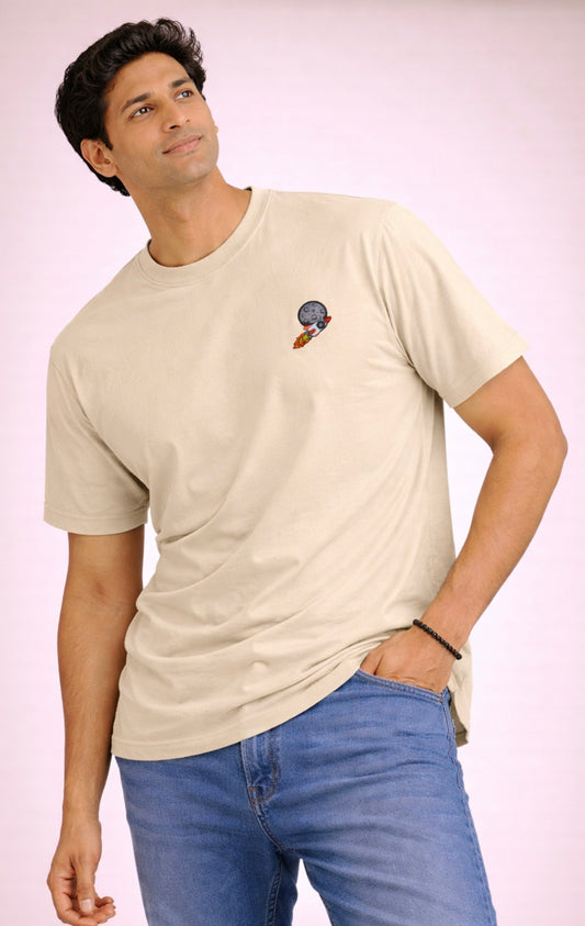 Man wearing a beige t-shirt with a small graphic on a pink background