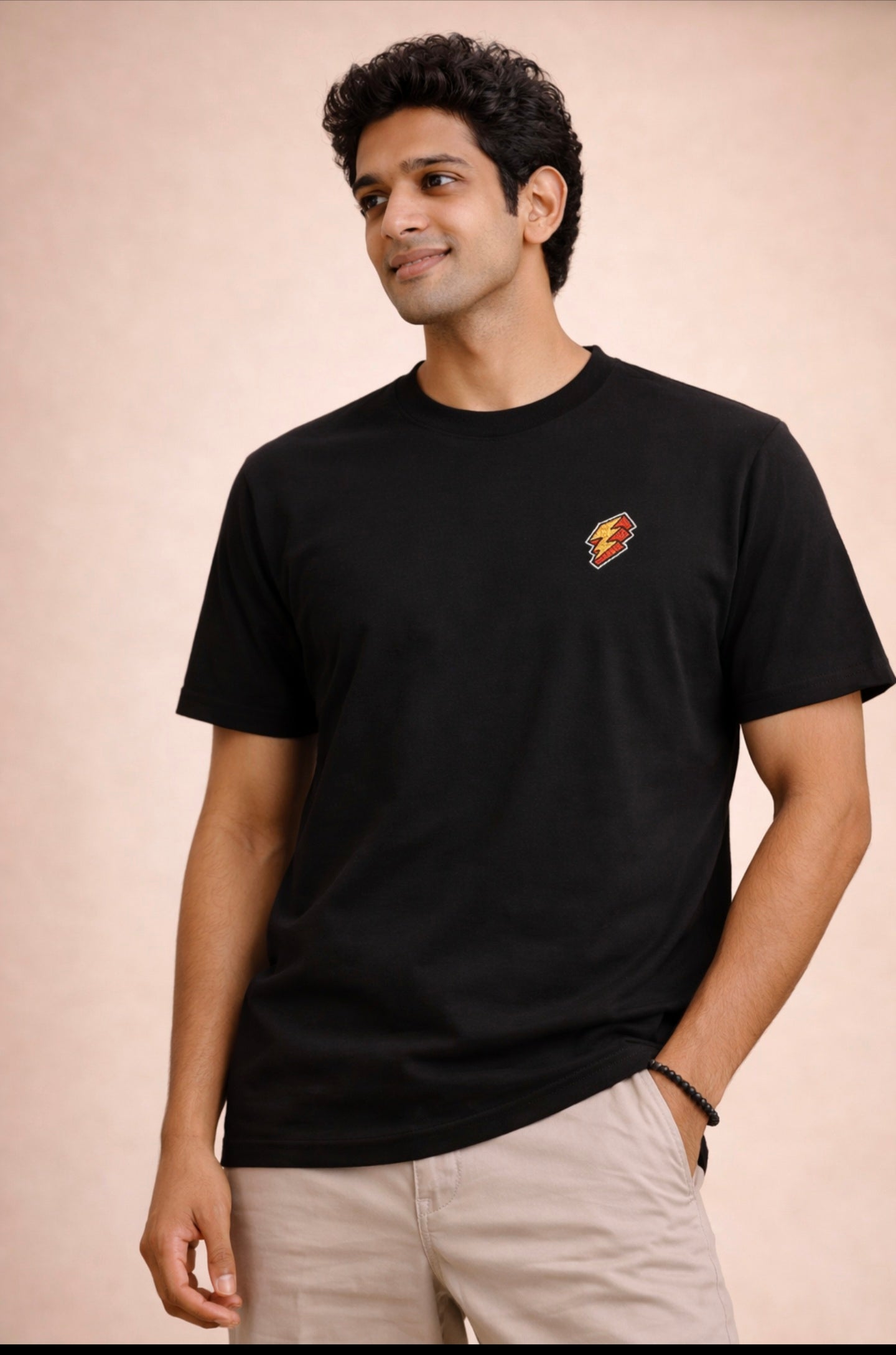 Man wearing a black t-shirt with a small logo on a beige background
