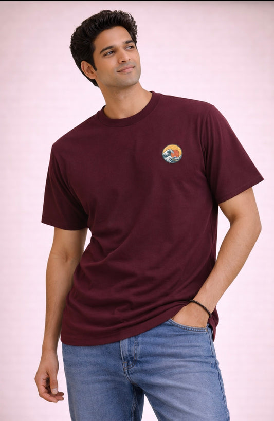 Man wearing a maroon t-shirt with a logo on a light pink background