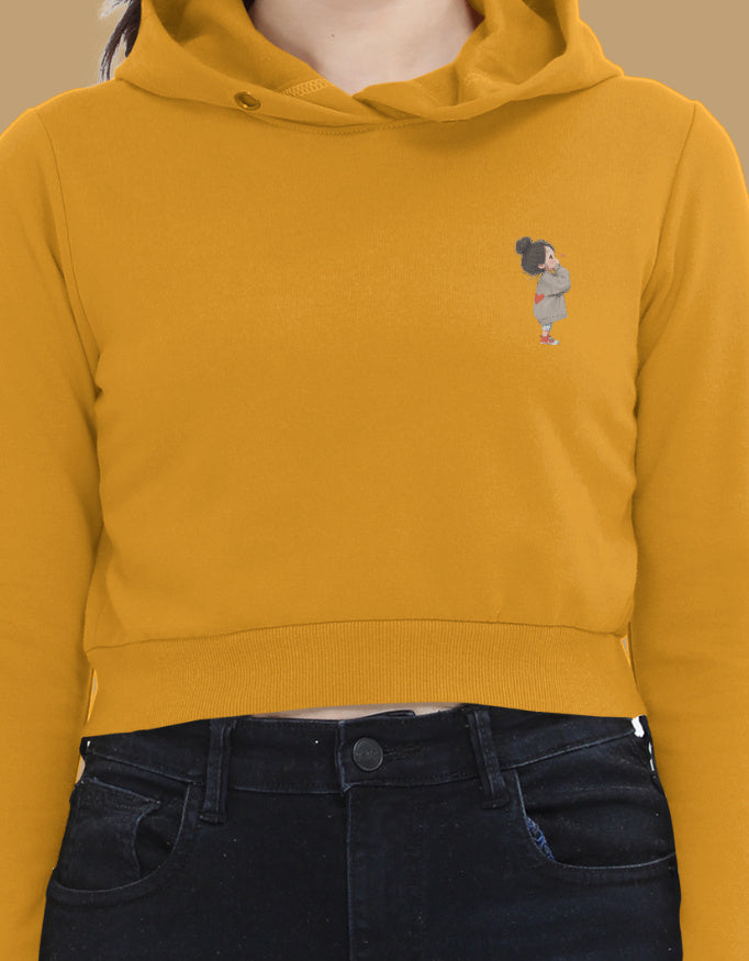 Women’s Mustard Yellow cropped hoodie with minimal left-chest cartoon graphic – stylish lightweight sweatshirt for casual wear.