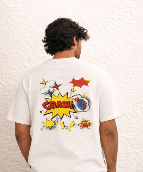 Person wearing a white t-shirt with colorful graphic designs on the back against a textured white wall.